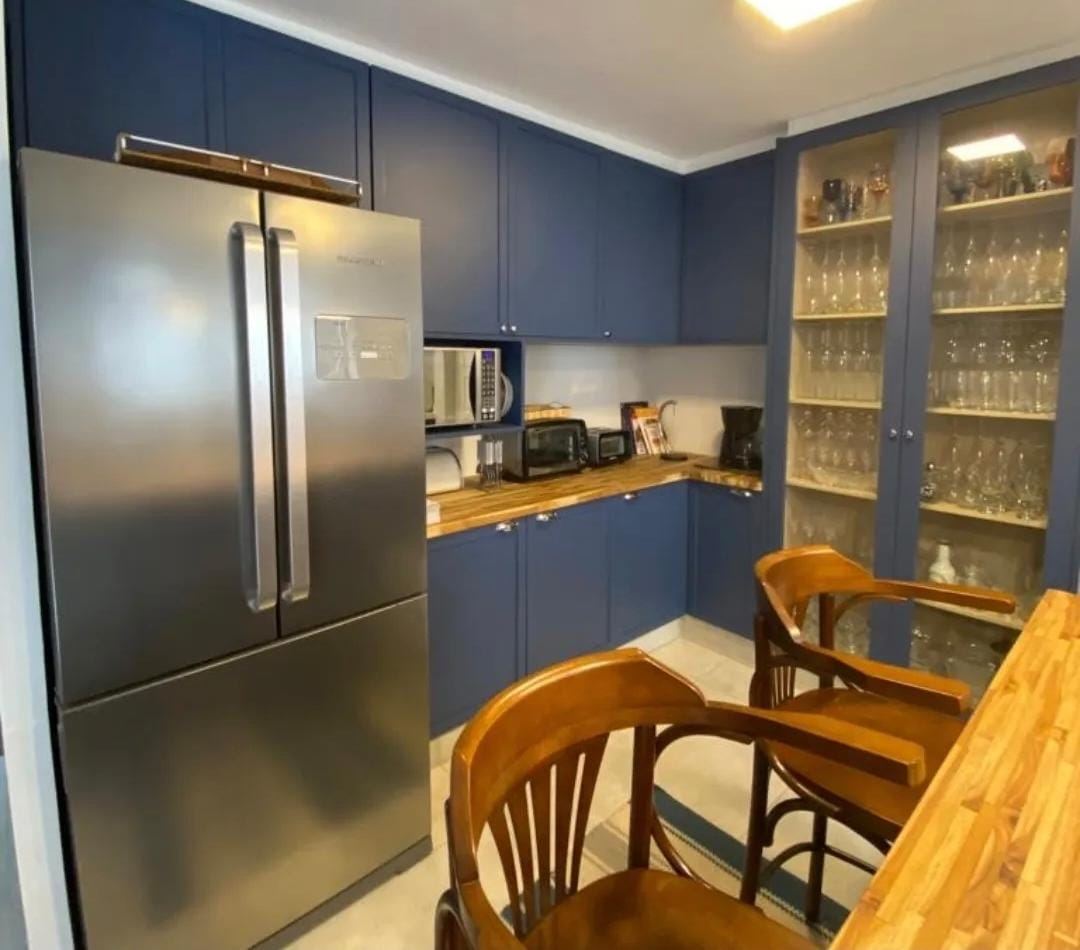 Cozinha azul com cristaleira e bancada de madeira